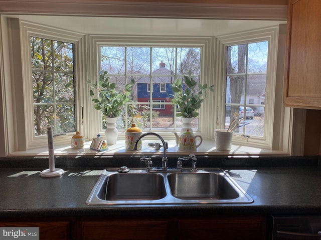 kitchen featuring dark countertops, a healthy amount of sunlight, and a sink