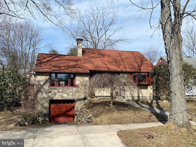 view of front of property with a shingled roof, an attached garage, driveway, and a chimney