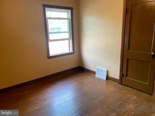 spare room featuring visible vents, plenty of natural light, baseboards, and dark wood finished floors