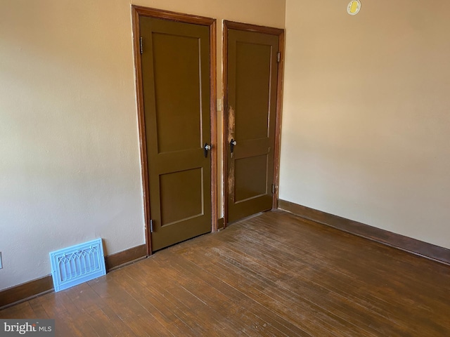 empty room with visible vents, baseboards, and hardwood / wood-style floors