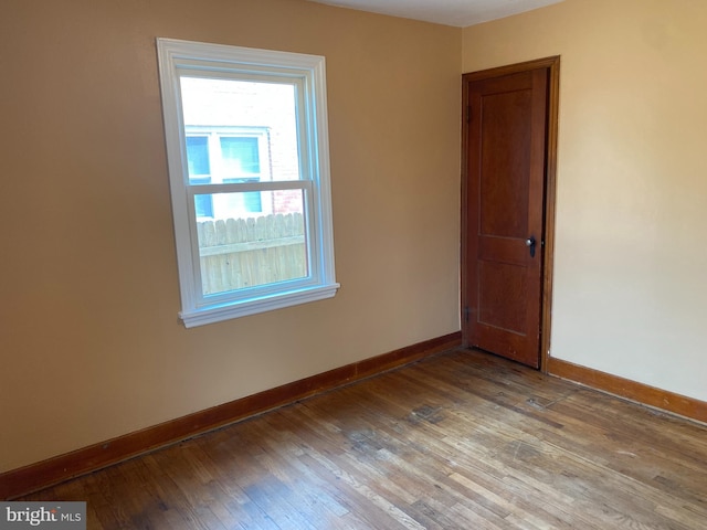 spare room with baseboards and wood-type flooring