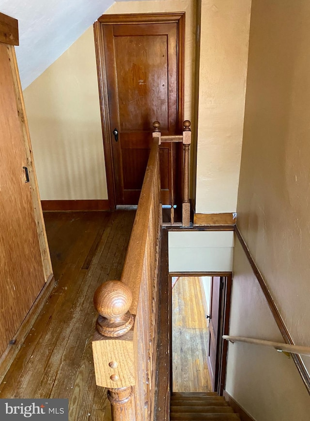 stairway with baseboards, lofted ceiling, and hardwood / wood-style floors