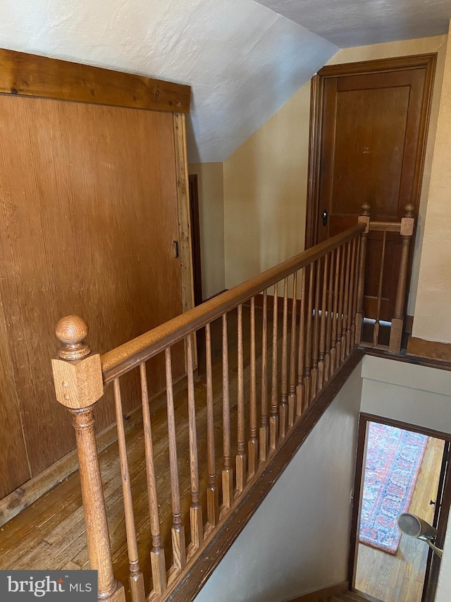 stairway featuring wood finished floors and vaulted ceiling