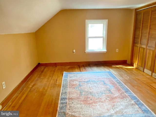 additional living space with baseboards, light wood-type flooring, and lofted ceiling