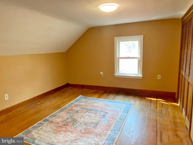 bonus room with light wood-type flooring, baseboards, and vaulted ceiling