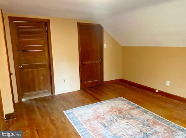 bonus room featuring vaulted ceiling, baseboards, and wood finished floors