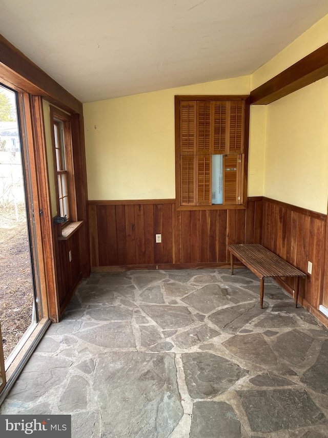 interior space with a wainscoted wall, stone floors, and wooden walls