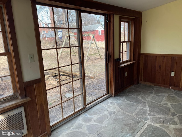 entryway featuring stone flooring, wooden walls, and wainscoting