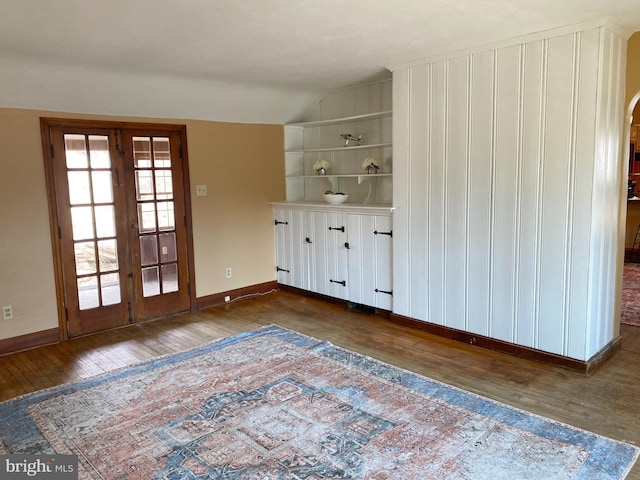 interior space featuring hardwood / wood-style floors, vaulted ceiling, french doors, and baseboards