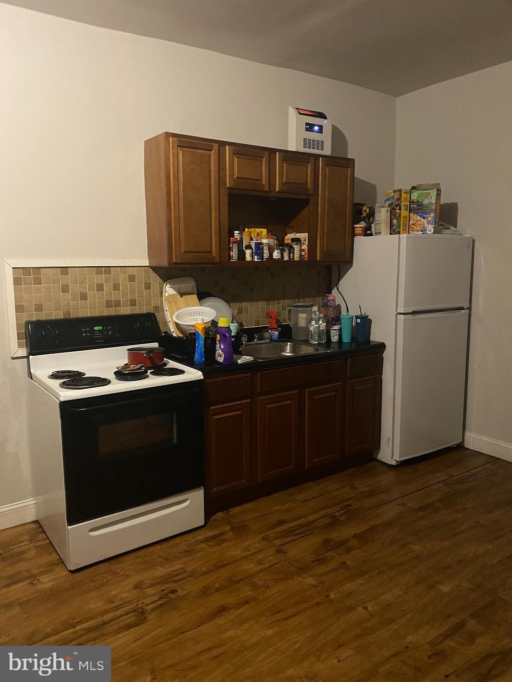 kitchen featuring dark hardwood / wood-style floors, dark brown cabinetry, white appliances, and sink