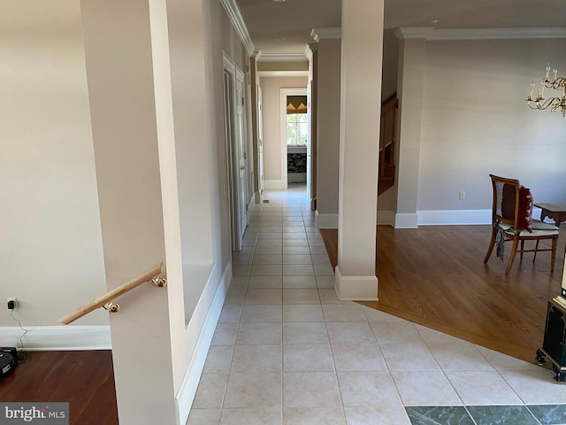 hallway with light tile patterned floors, an inviting chandelier, and ornamental molding