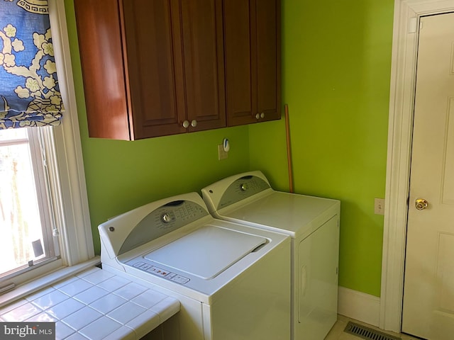 clothes washing area featuring light tile patterned floors, cabinets, independent washer and dryer, and a wealth of natural light