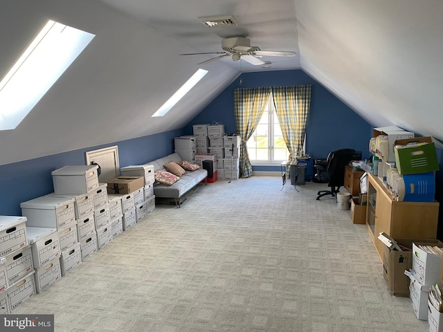 interior space featuring vaulted ceiling with skylight, ceiling fan, and light colored carpet