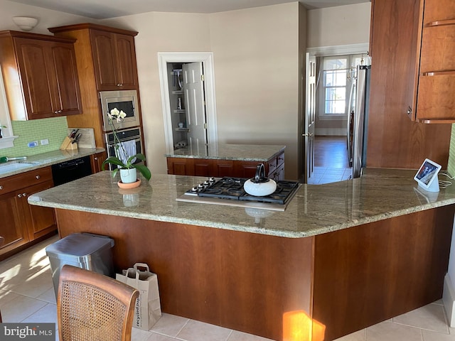 kitchen with tasteful backsplash, light stone countertops, light tile patterned floors, and stainless steel appliances