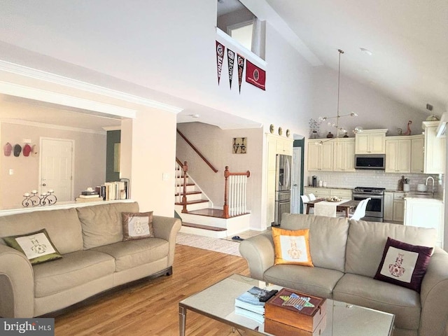 living room with light hardwood / wood-style floors, high vaulted ceiling, and crown molding