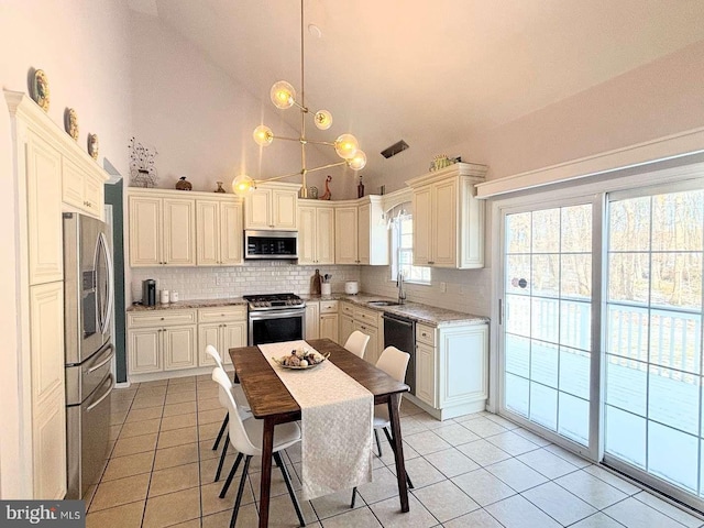 kitchen featuring pendant lighting, high vaulted ceiling, decorative backsplash, light tile patterned floors, and appliances with stainless steel finishes