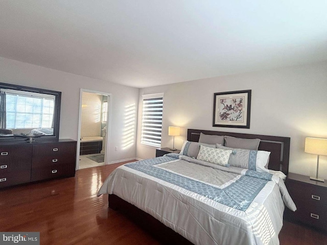 bedroom with ensuite bath and dark wood-type flooring