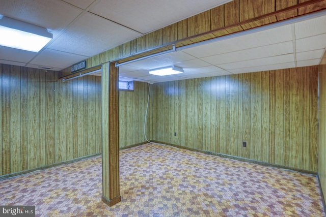 basement with a paneled ceiling and wooden walls