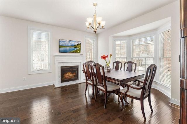 dining area featuring a high end fireplace, dark hardwood / wood-style floors, and a notable chandelier