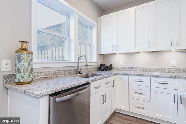 kitchen with light stone countertops, dishwasher, sink, dark wood-type flooring, and white cabinets