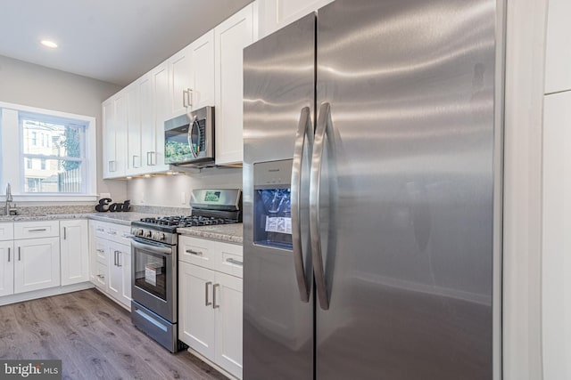 kitchen with light stone counters, white cabinets, and stainless steel appliances