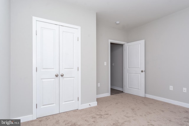 unfurnished bedroom featuring light colored carpet and a closet