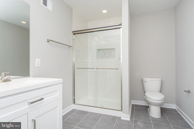 bathroom with tile patterned floors, a shower with door, vanity, and toilet