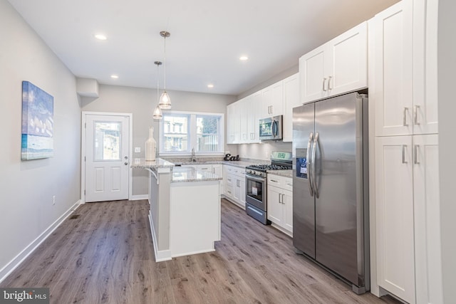 kitchen with light stone countertops, stainless steel appliances, pendant lighting, a center island, and white cabinetry