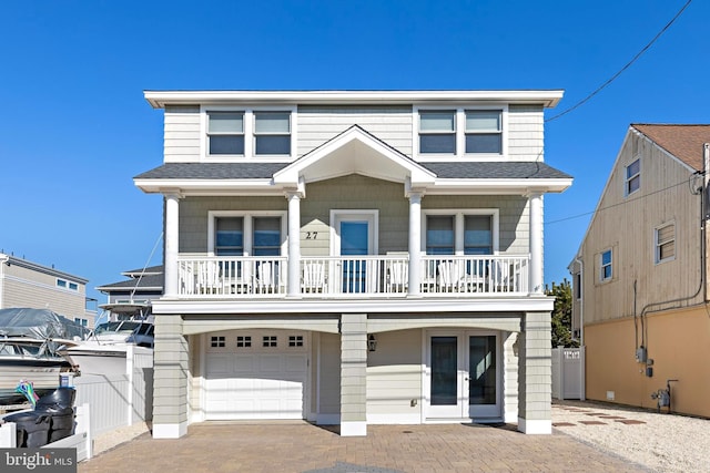 view of front of property featuring a garage, a balcony, and french doors