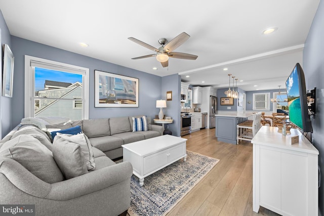 living room featuring light wood-type flooring, ceiling fan, and a healthy amount of sunlight