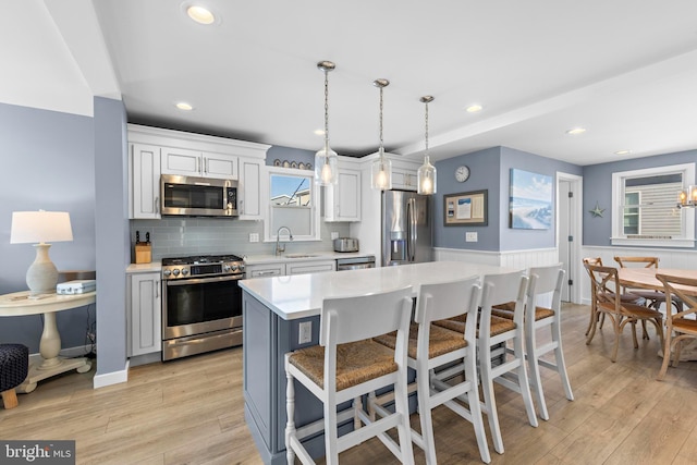 kitchen with appliances with stainless steel finishes, a breakfast bar, sink, decorative light fixtures, and a center island