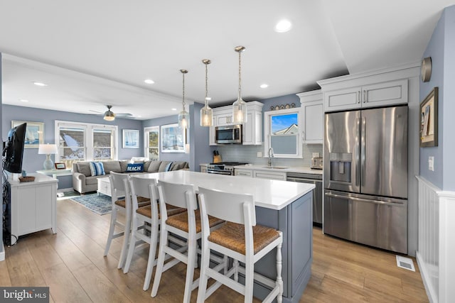 kitchen with backsplash, a breakfast bar, stainless steel appliances, a center island, and hanging light fixtures