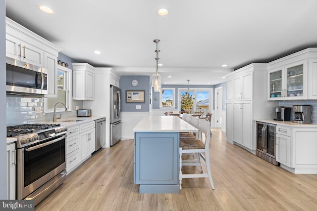 kitchen featuring appliances with stainless steel finishes, sink, white cabinets, wine cooler, and hanging light fixtures