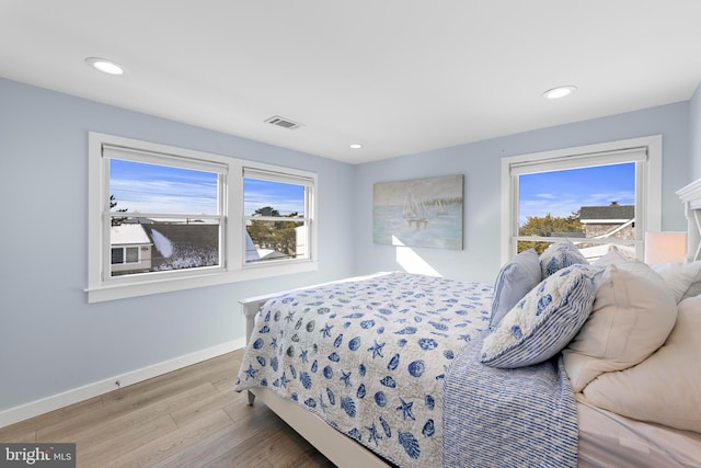 bedroom with multiple windows and light hardwood / wood-style flooring