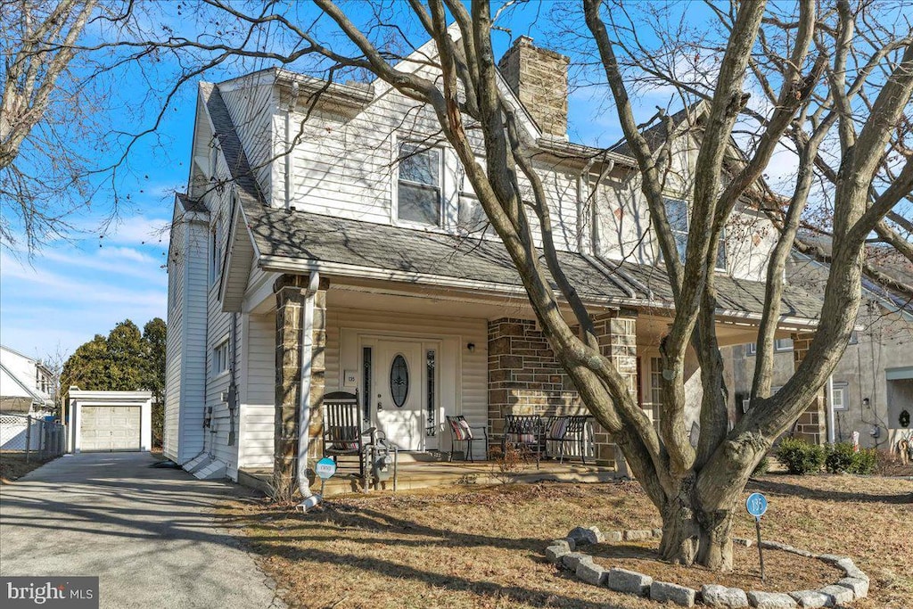 view of front facade featuring covered porch, a garage, and an outbuilding