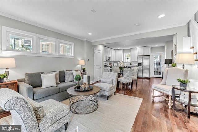 living room featuring dark hardwood / wood-style flooring, a wealth of natural light, and crown molding