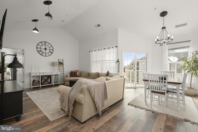 living room featuring dark wood-type flooring, high vaulted ceiling, and a chandelier