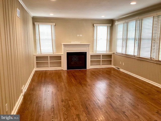 unfurnished living room featuring ornamental molding, hardwood / wood-style floors, and wooden walls