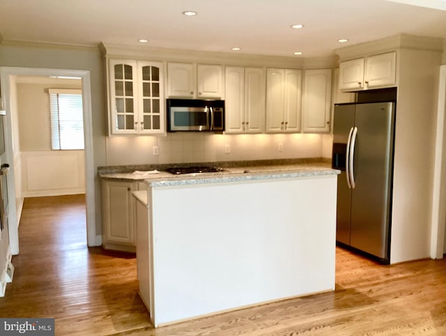 kitchen with appliances with stainless steel finishes, light hardwood / wood-style floors, and white cabinetry