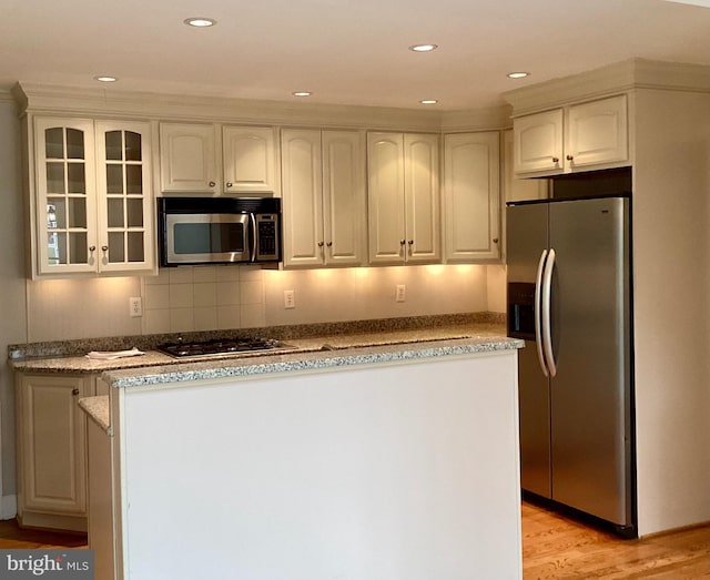 kitchen with white cabinets, appliances with stainless steel finishes, light hardwood / wood-style flooring, and decorative backsplash