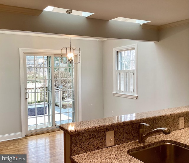 interior space featuring sink, ornamental molding, hanging light fixtures, light stone countertops, and a chandelier