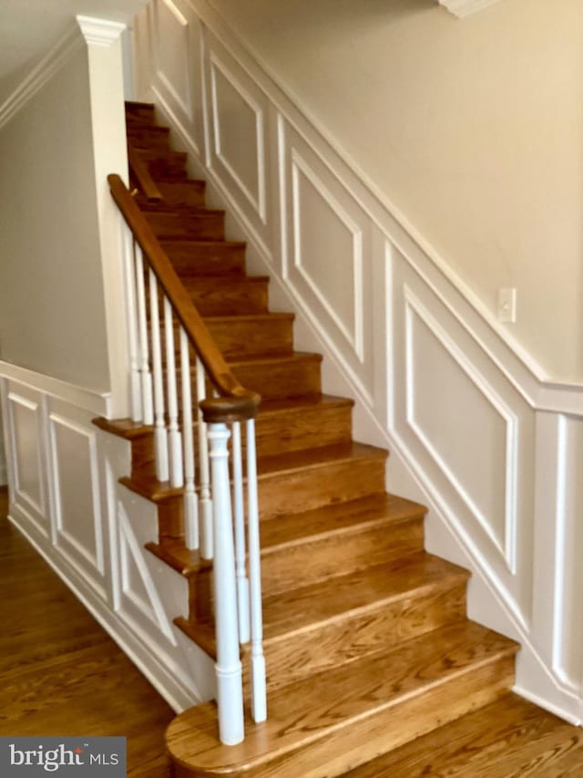 stairs with ornamental molding and hardwood / wood-style floors