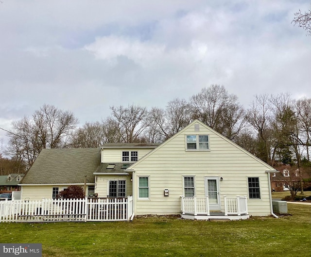 rear view of house featuring central AC and a yard