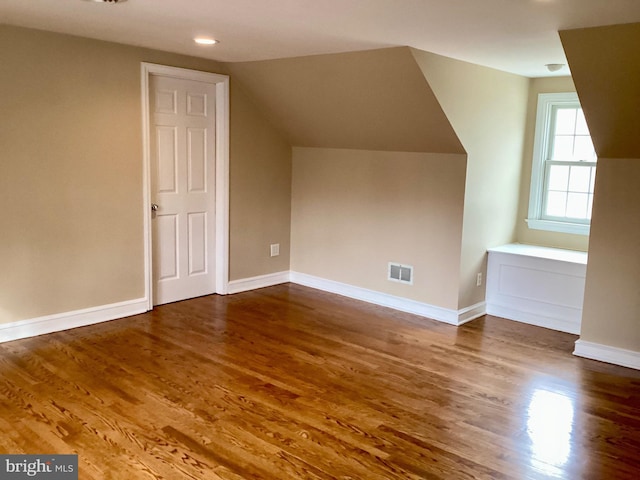 bonus room with dark wood-type flooring and vaulted ceiling