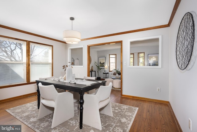 dining area with crown molding, baseboards, and wood finished floors