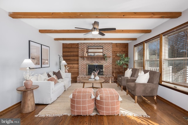 living area featuring beam ceiling, baseboards, and hardwood / wood-style flooring