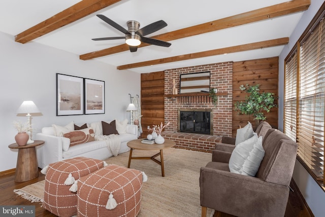 living room featuring a fireplace, beam ceiling, wood finished floors, and baseboards