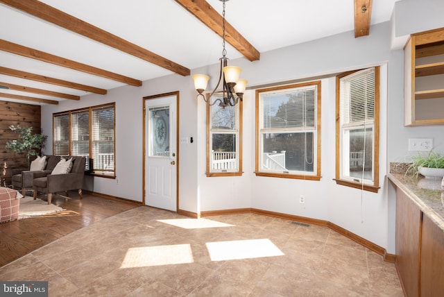 unfurnished dining area with beamed ceiling, a notable chandelier, baseboards, and visible vents