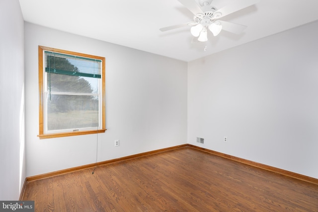 empty room featuring visible vents, a ceiling fan, baseboards, and wood finished floors