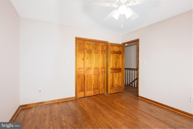 unfurnished bedroom with wood finished floors, visible vents, a closet, and baseboards